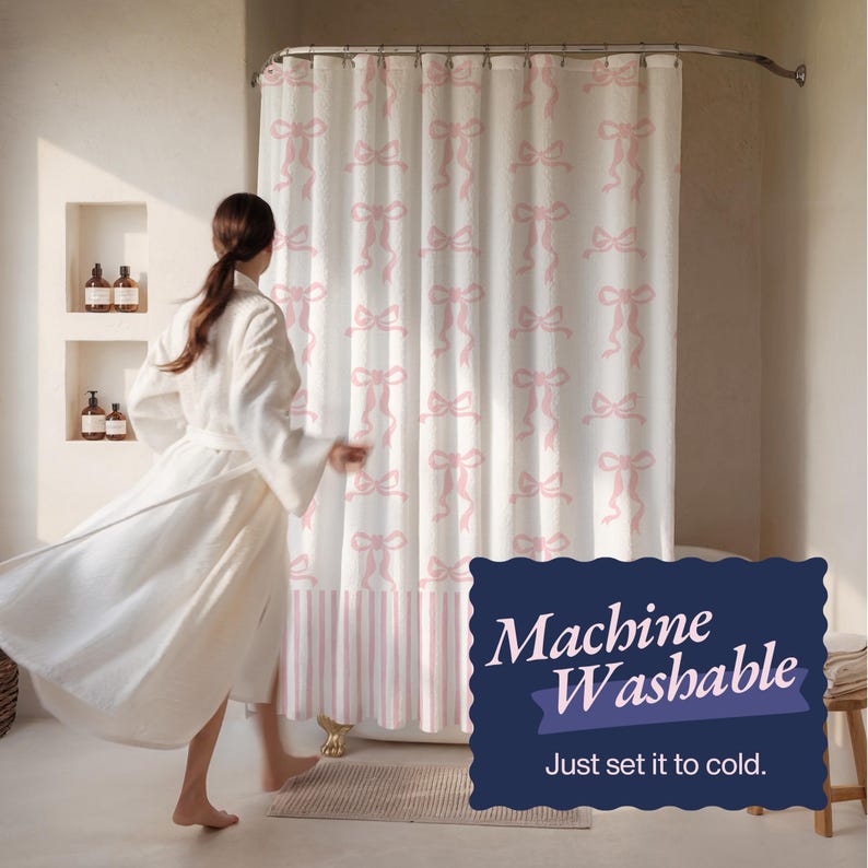 May include: White shower curtain with a repeating pink bow pattern. The bottom section has pink and white vertical stripes. The text on the image says "Machine Washable" and "Just set it to cold."