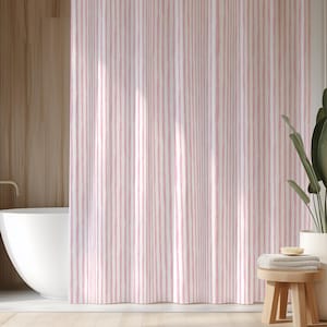 May include: A pink and white striped shower curtain hangs in front of a white bathtub. The curtain has vertical stripes of varying widths. A wooden stool with towels and a plant in a white pot are in the background.