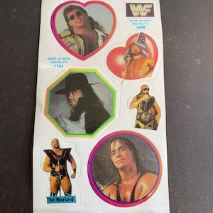 May include: A sheet of vintage wrestling stickers featuring various wrestlers in action poses. The stickers are in various shapes, including hearts and circles, with the WWF logo and text "Made in India Novelty".