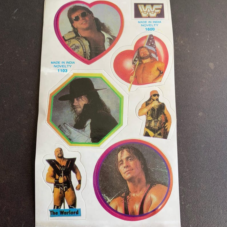 May include: A sheet of vintage wrestling stickers featuring various wrestlers in action poses. The stickers are in various shapes, including hearts and circles, with the WWF logo and text "Made in India Novelty".