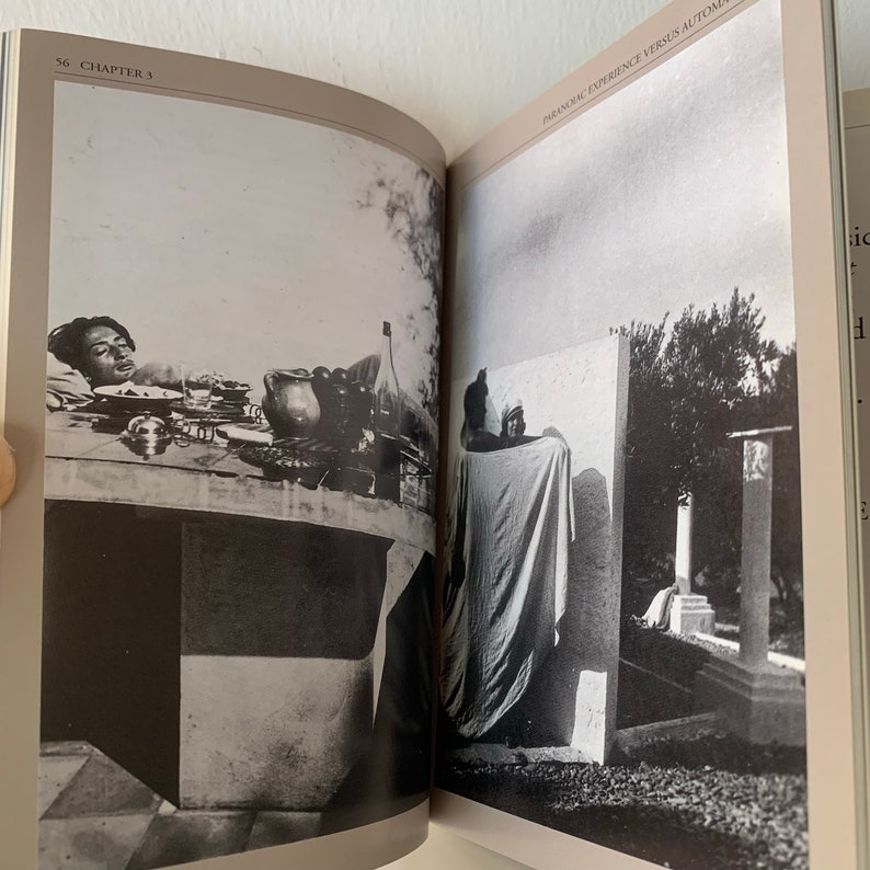 May include: A black and white photograph of a person lying on a table with a glass of wine and a plate of food. The photo is from a book titled "Paranoid Experience Versus Automatic Writing".