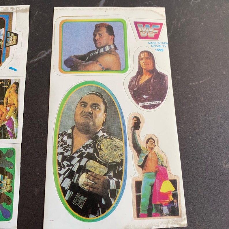 May include: Sheet of vintage WWF stickers featuring wrestlers. The stickers include images of wrestlers in action poses, with the WWF logo and text. The stickers are printed on a white background with colorful borders and text that reads "Made in India Novelty 1599."