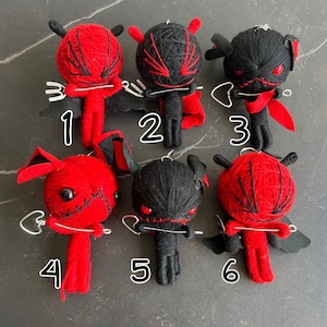 Puede incluir: Se muestran seis muñecos de diablo hechos a mano. Cada muñeco tiene una cabeza envuelta en hilo con cuernos, alas y un cuerpo pequeño. Los muñecos son principalmente rojos y negros, con variaciones de diseño y expresión. Cada muñeco tiene un lazo de metal para colgar.