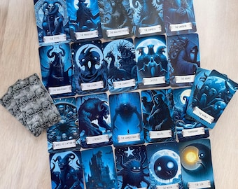 Op de afbeelding: Een set van 22 tarotkaarten met donkerblauwe achtergronden en illustraties van verschillende wezens en symbolen. De kaarten zijn gerangschikt in een rasterpatroon op een houten oppervlak.