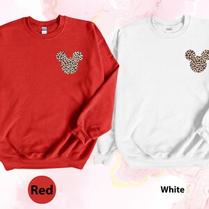 May include: Red and white sweatshirts with a leopard print Mickey Mouse design on the chest. The red sweatshirt has the word "Red" in a circle at the bottom. The white sweatshirt has the word "White" in a circle at the bottom.