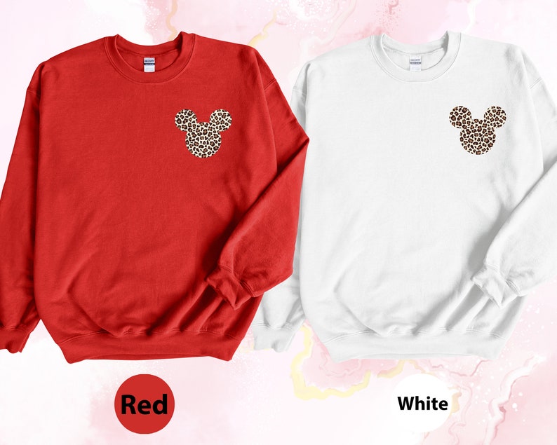 May include: Red and white sweatshirts with a leopard print Mickey Mouse design on the chest. The red sweatshirt has the word "Red" in a circle at the bottom. The white sweatshirt has the word "White" in a circle at the bottom.