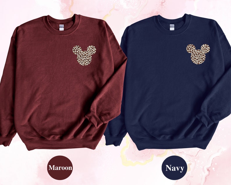 May include: Two sweatshirts, one maroon and one navy, each featuring a leopard print Mickey Mouse head design on the upper left chest. The maroon sweatshirt has the word "Maroon" below it. The navy sweatshirt has the word "Navy" below it.