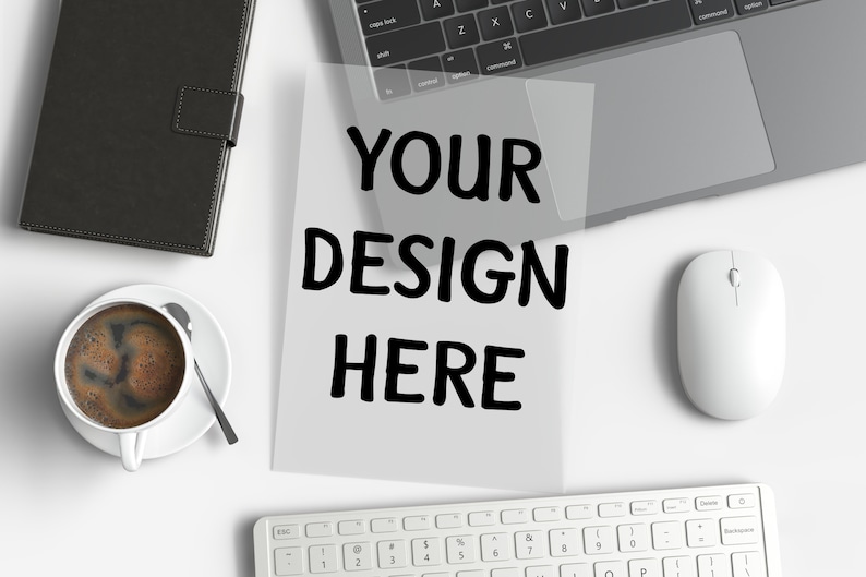 May include: A workspace scene with a laptop, keyboard, and mouse. A sheet of paper with the text "YOUR DESIGN HERE" is centered. A cup of coffee and a black notebook are also present.