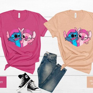 以下が含まれることがあります： リロ＆スティッチのスティッチとエンジェルが描かれたグラフィックのTシャツ2枚。左側のシャツはピンク、右側のシャツはピーチカラーです。