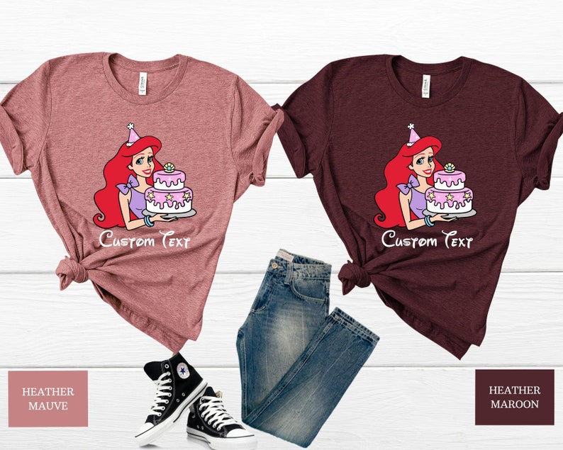 Pode incluir: Duas camisetas com uma imagem de desenho animado de Ariel da Pequena Sereia segurando um bolo de anivers&aacute;rio rosa e branco. O texto "Custom Text" &eacute; impresso abaixo da imagem. A camiseta &agrave; esquerda &eacute; de cor malva mesclada e a camiseta &agrave; direita &eacute; de cor marrom mesclada.