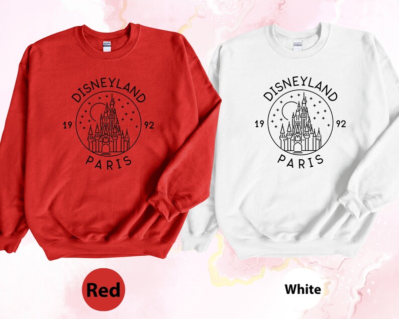 Puede incluir: Dos sudaderas, una roja y otra blanca, con un gr&aacute;fico negro del castillo de Disneyland Par&iacute;s y el texto "DISNEYLAND PARIS 1992".