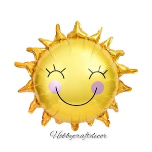 May include: A gold foil balloon shaped like a smiling sun with white polka dots. The sun has closed eyes and a big smile.