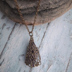 May include: A delicate gold chain necklace with a pendant featuring a purple amethyst stone encased in an intricate filigree design.