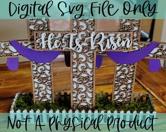 May include: Three wooden crosses with intricate cutouts and a purple banner that reads "He Is Risen". The crosses are set in a white picket fence planter with green moss. Digital SVG file only, not a physical product.