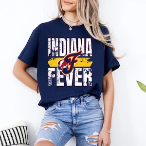 May include: A navy blue short-sleeved t-shirt featuring a distressed white graphic that reads INDIANA FEVER. The design includes a yellow horizontal bar and a stylized letter F incorporating a red, white, and blue basketball graphic.