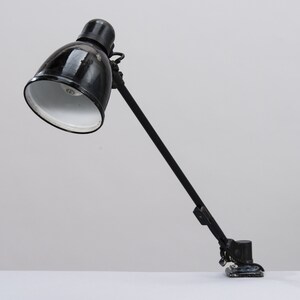 May include: Black metal desk lamp with a black and white shade and a clamp base.