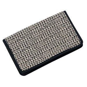 Könnte beinhalten: Ein rechteckiges Etui mit Reißverschluss, das ein sich wiederholendes schwarz-cremefarbenes Muster aus kleinen, abgewinkelten blattartigen Formen aufweist. Das Etui hat einen einfarbigen schwarzen Stoffrand und einen schwarzen Reißverschluss.