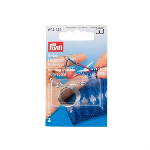 Könnte beinhalten: Ein silberner Strickfingerhut aus Metall mit Federdesign. Die Verpackung ist blau und weiß mit dem Text "Knitting thimble Norwegian" und "Strick-Fingerhut Norweger".