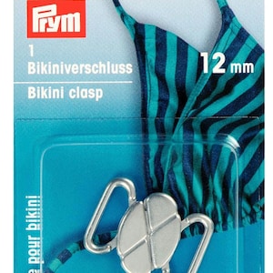 Op de afbeelding: Zilveren bikini-sluiting met een maat van 12 mm. De sluiting wordt getoond op een blauwe en groene gestreepte stoffen achtergrond. De verpakking bevat de tekst "Bikiniverschluss" en "Bikini clasp".