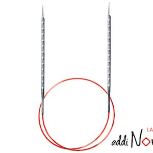 Könnte beinhalten: Ein Paar silberne Stricknadeln, die durch eine rote Schnur verbunden sind. Die Nadeln sind mit "addi Novel Lace" beschriftet.