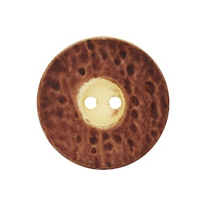 Könnte beinhalten: Ein runder Knopf mit einer braunen, strukturierten Oberfläche und zwei Löchern in der Mitte. Der Knopf hat eine hellbeige Mitte und ein gesprenkeltes Muster auf dem äußeren Ring. Geeignet für Nähprojekte.