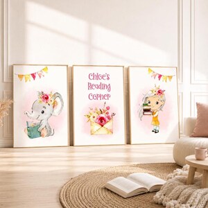 Könnte beinhalten: Drei gerahmte Aquarelldrucke mit einem Lesethema. Die Drucke zeigen einen Elefanten, der ein Buch liest, einen floralen Umschlag und ein Mädchen, das Bücher hält. Der Text "Chloe's Reading Corner" steht auf dem mittleren Druck. Jeder Druck hat einen goldenen Rahmen.