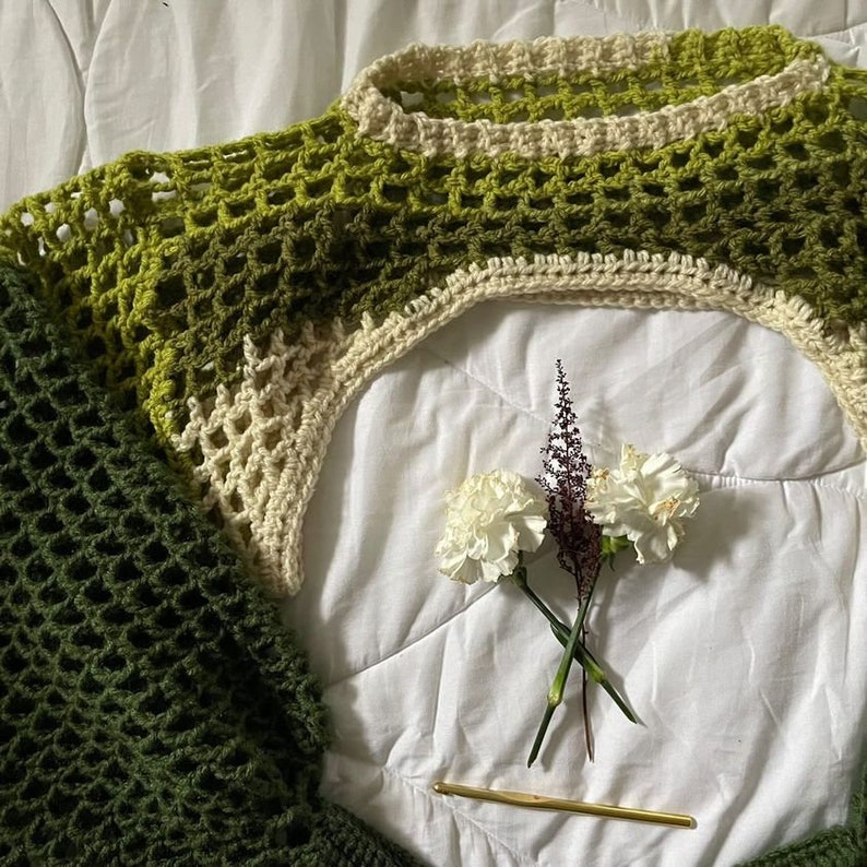 green and white sleeves flatlay, flowers and crochet hook in center, green crochet bolero, green crochet shrug