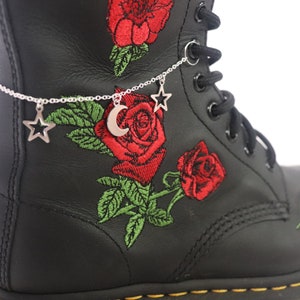May include: Black leather boots with red rose embroidery and a silver chain ankle bracelet with a crescent moon and star charms.