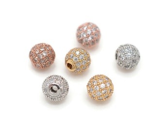 May include: Six round beads with a pave setting of clear rhinestones. The beads are in three different metal finishes: silver, gold, and rose gold.