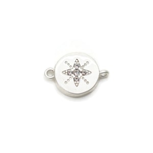 May include: Silver-toned round charm with a clear crystal star in the center. The charm has a loop on each side for attaching to a bracelet or necklace.