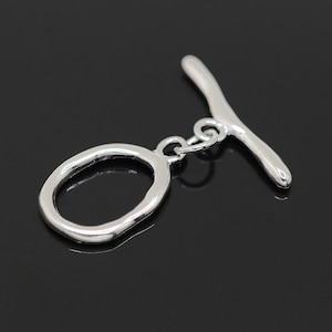 May include: Silver toggle clasp with a smooth, oval ring and a straight bar. The clasp is designed for jewelry making.