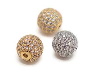 May include: Three round beads with a hole through the center. The beads are covered in small, clear rhinestones. One bead is gold, one is silver, and one is a mix of gold and silver.