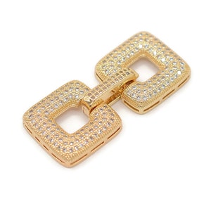 May include: Gold-tone chain link with a square design, featuring a pave setting of clear rhinestones.
