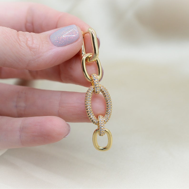 Pode incluir: Brincos de corrente de elo dourado com pedras de zirc&ocirc;nia transparentes.