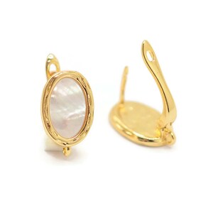 Op de afbeelding: Een paar gouden oorbellen met een ovale inleg van wit parelmoer. De oorbellen hebben een eenvoudig, elegant ontwerp.