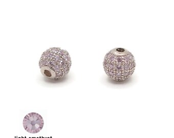 May include: Two silver round beads with a hole in the center. The beads are covered in small light amethyst colored rhinestones.