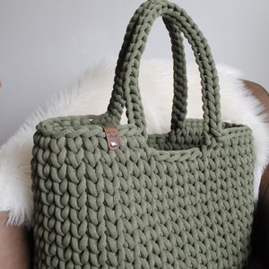 May include: A large, green crocheted tote bag with a brown leather tag that says "Woven Craft".