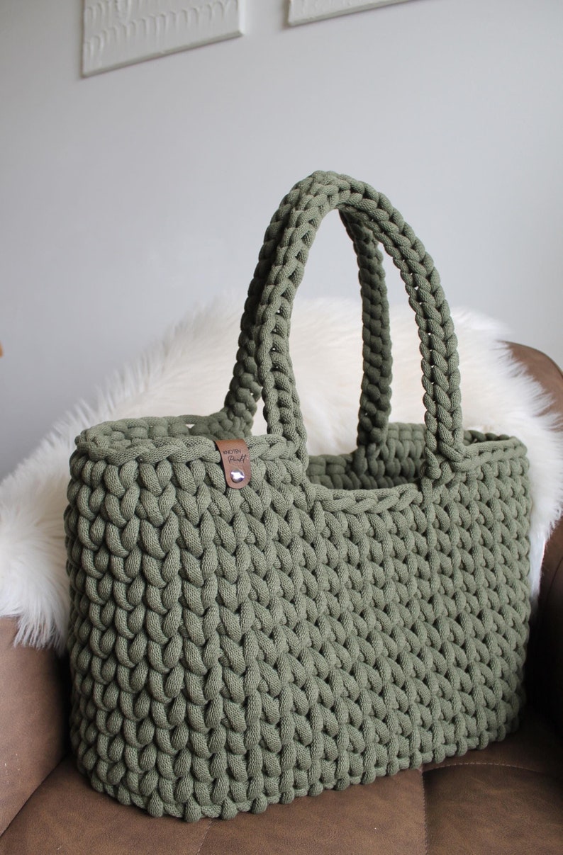 May include: A large, green crocheted tote bag with a brown leather tag that says "Woven Craft".