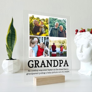 May include: A clear acrylic photo frame with a collage of four photos of a man with family and friends. The frame has a wooden stand and the text "GRANDPA" in black letters. The text below reads "No cowboy was ever faster on the draw than a grandparent pulling a baby picture out of a wallet."