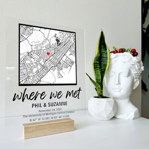 Puede incluir: Un letrero de acr&iacute;lico transparente con un mapa en blanco y negro de una ciudad. Un coraz&oacute;n rojo marca el lugar donde Phil y Suzanne se conocieron el 24 de noviembre de 2001 en el campus central de la Universidad de Michigan. El letrero dice "where we met" e incluye las coordenadas N 42&deg; 16' 37.681, W 83&deg; 44' 17.692.