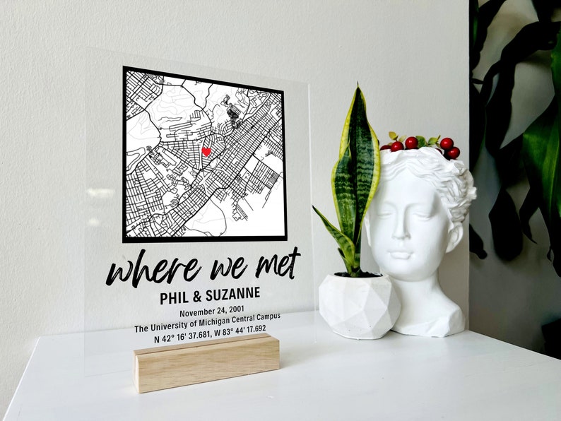 Puede incluir: Un letrero de acr&iacute;lico transparente con un mapa en blanco y negro de una ciudad. Un coraz&oacute;n rojo marca el lugar donde Phil y Suzanne se conocieron el 24 de noviembre de 2001 en el campus central de la Universidad de Michigan. El letrero dice "where we met" e incluye las coordenadas N 42&deg; 16' 37.681, W 83&deg; 44' 17.692.