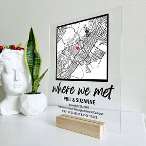 Puede incluir: Un letrero de acr&iacute;lico transparente con texto negro y un mapa en blanco y negro. El texto dice "where we met", "Phil & Suzanne", "November 24, 2001", "The University of Michigan Central Campus", y "N 42&deg; 15' 37.681, W 83&deg; 44' 17.692". Un coraz&oacute;n rojo est&aacute; marcado en el mapa.