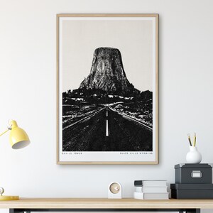 May include: Black and white illustration of Devils Tower National Monument in Black Hills, Wyoming. The image shows a road leading up to the tower.