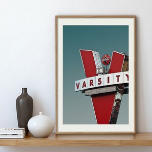 May include: A vintage red and white sign with the text "The Varsity" and "Since 1929" against a blue sky.