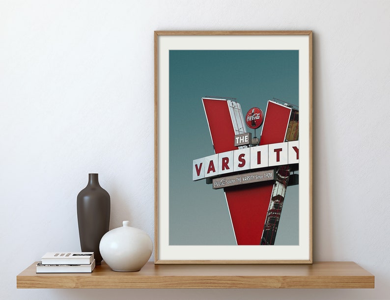 May include: A vintage red and white sign with the text "The Varsity" and "Since 1929" against a blue sky.