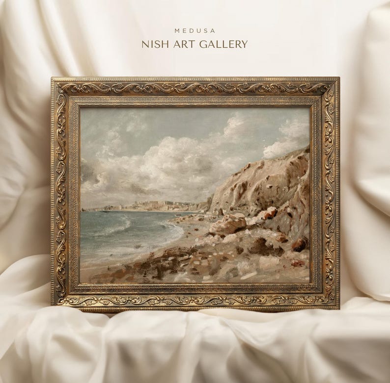 May include: A framed landscape painting of a coastal scene with a rocky cliff, beach, and ocean under a cloudy sky. The ornate gold frame surrounds the artwork. The text "MEDUSA NISH ART GALLERY" is at the top.