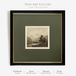 May include: A square framed wall art piece featuring a black wooden frame with a thin gold inner border and a dark olive green mount. The print depicts a sepia-toned mountain landscape with a lake and trees. Text reads NISH ART GALLERY VIVA COLLECTION.