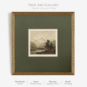 May include: A square framed art print featuring a sepia-toned landscape of mountains, a lake, and trees. The artwork is encased in a dark olive green mat and a textured gold-coloured frame. Text at the top reads NISH ART GALLERY TROYA COLLECTION.