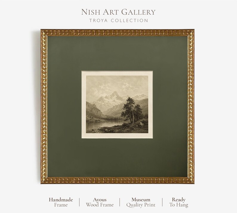 May include: A square framed art print featuring a sepia-toned landscape of mountains, a lake, and trees. The artwork is encased in a dark olive green mat and a textured gold-coloured frame. Text at the top reads NISH ART GALLERY TROYA COLLECTION.