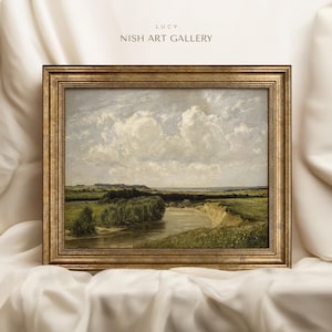 May include: A framed landscape painting depicting a river winding through a green field with a cloudy sky in the background. The frame is gold with a decorative border.